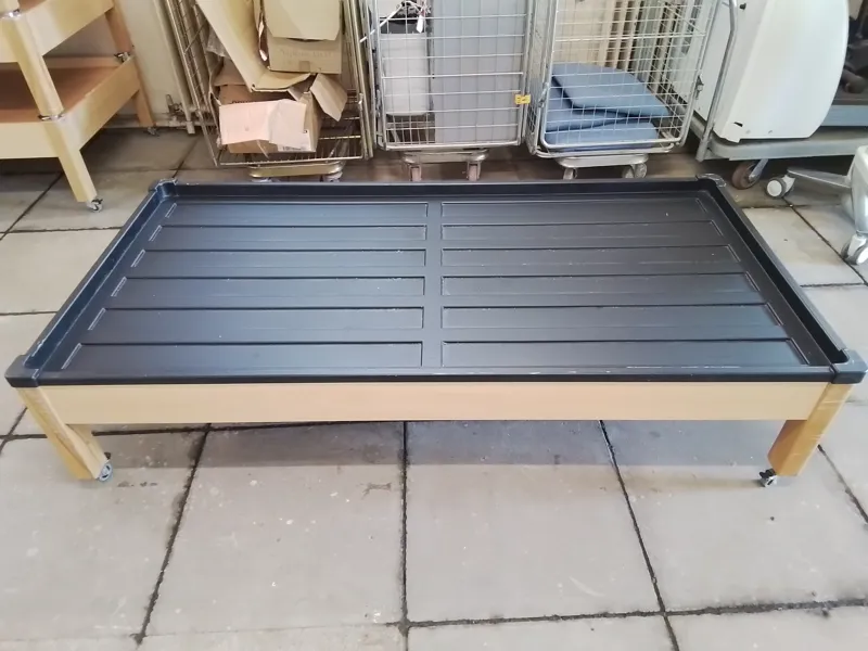 Wooden framed single bed with black plastic mattress frame